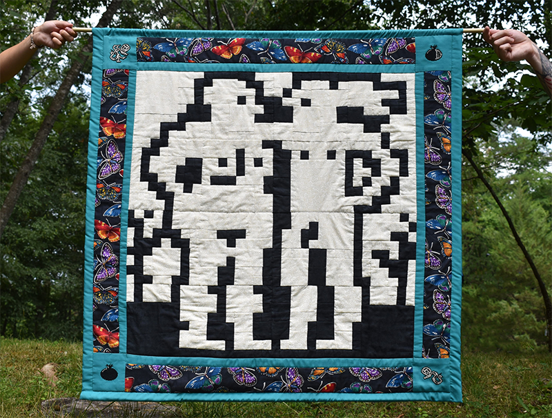 A quilt with a central image of Adam and Eve rendered by a 32 by 32 grid.